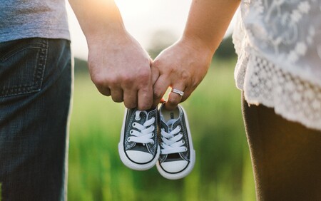 A couple holding hands and a pair of tiny baby trainers